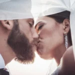 Primo piano bacio sposi sotto il velo bianco, orecchini pendenti di diamanti | Fabio Zenoardo