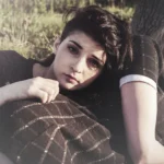 Primo piano di due ragazze vicine, appoggiate a un albero, sguardi verso la telecamera, fotografia moda