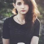 Ritratto di ragazza con tatuaggio floreale sul braccio, capelli scuri, sguardo diretto, fashion photography