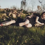 Due modelle sdraiate nell'erba ai piedi di un albero, atmosfera rilassata, fotografia fashion Liguria