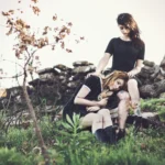 Due ragazze sedute vicino a muri a secco, una appoggia la testa sull'altra, fotografia moda Imperia