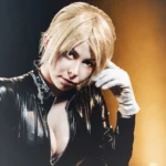 Ritratto di Yuriko Tiger in tuta di latex nera e guanti bianchi, sguardo seducente, fotografia cosplay Liguria