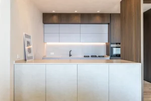 Cucina moderna con isola centrale, pensili in legno scuro, basi bianche e illuminazione LED sottopensile