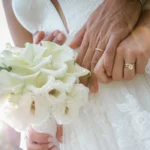 Mani degli sposi con fedi nuziali accostate a un bouquet di calle bianche | Fabio Zenoardo