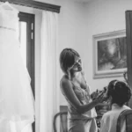 Scena ampia del getting ready in bianco e nero, sposa truccata con abito appeso sullo sfondo | Fabio Zenoardo