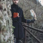 Attore Ghost Tour con barbagianni sul guanto e libro arancione, ambientazione medievale Liguria