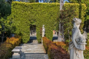 Giardino italiano formale con siepi geometriche, vialetto in pietra e statue classiche di villa di lusso