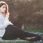 Fotografo artistico Imperia - Yuriko sdraiata muretto camicia bianca jeans scuri parco