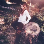 Fotografo artistico Liguria - Yuriko seduta tronco albero giardino autunnale camicia bianca