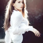 Fotografo ritratto Liguria - Yuriko seduta muretto camicia bianca posa laterale parco
