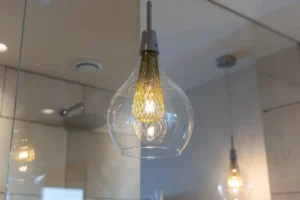 Primo piano di lampadario di design in vetro soffiato con filamento dorato intrecciato, interno luxury
