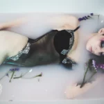 Fotografo boudoir Liguria - modella distesa fiori trucco marcato