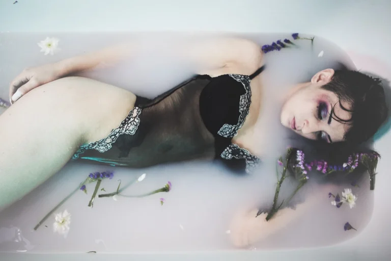 Fotografo boudoir Liguria - modella distesa fiori trucco marcato