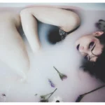Fotografo boudoir Liguria - modella distesa vasca fiori occhi chiusi