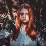 Fotografo moda Liguria - modella foglie scure luce naturale capelli rossi