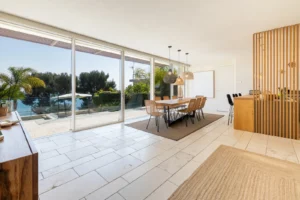 Open space con zona pranzo, pavimento in piastrelle e grande vetrata aperta su piscina e mare, Liguria