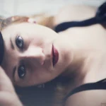 Fotografo boudoir Imperia - modella distesa occhi azzurri veletta nera