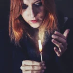 Fotografo dark Imperia - modella fiammifero acceso mani capelli rossi
