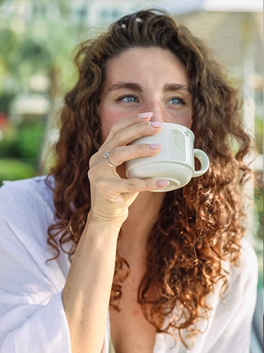 Home Ritratto lifestyle di ragazza riccia con tazza di caffè, luce naturale, stile social media