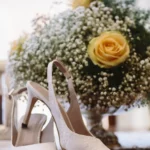 Scarpe da sposa slingback in pizzo bianco accanto a bouquet di rose gialle | Fabio Zenoardo