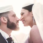Sposi quasi si baciano sotto il velo bianco, sguardi vicini e sorrisi complici | Fabio Zenoardo
