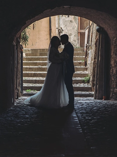 Home Silhouette romantica di sposi che si abbracciano in un arco medievale ligure