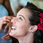 Sposa ride con rose rosse tra i capelli scuri durante la preparazione del matrimonio | Fabio Zenoardo