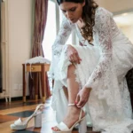Sposa in abito di pizzo bianco allaccia le scarpe con plateau | Fabio Zenoardo fotografo matrimoni