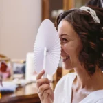 Sposa ride nascondendosi dietro un ventaglio bianco, diadema tra i capelli ricci | Fabio Zenoardo