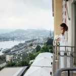 Sposa in abito bianco con bouquet sul balcone, panorama lacustre sullo sfondo | Fabio Zenoardo