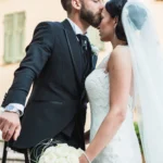 Sposo bacia teneramente la fronte della sposa con bouquet di rose bianche | Fabio Zenoardo