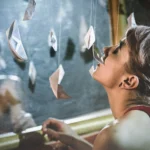 Fotografo creativo Imperia - modella distesa raggiunge barchette carta sospese
