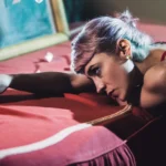 Fotografo fashion Liguria - modella distesa letto rosso mano allungata