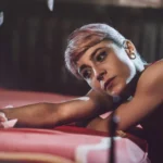 Fotografo ritratto Imperia - ritratto modella letto rosso sguardo diretto capelli rosa
