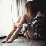 Fotografo ritratto Imperia - modella rannicchiata finestra camicia quadri