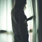Fotografo dark Liguria - silhouette modella finestra tende luce soffusa