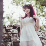 Fotografo fashion Imperia - modella abito bianco muro pietra bosco sguardo basso
