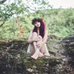 Fotografo artistico Liguria - modella capelli rossi seduta rocce muschio bosco