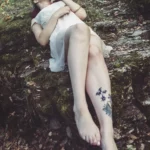 Fotografo fashion Imperia - modella distesa muschio tatuaggio gamba abito bianco