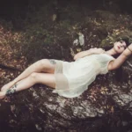 Fotografo fashion Imperia - modella abito bianco distesa rocce bosco