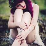 Fotografo artistico Imperia - modella rannicchiata tatuaggi gambe roccia muschio