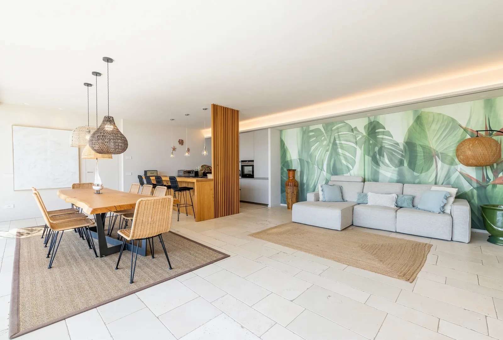 Ampio open space con zona pranzo in legno, cucina a vista e parete decorata, fotografia reale senza persone