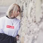 Fotografo fashion Liguria - modella t-shirt Evangelion sguardo basso muro pietra