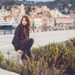 Fotografo fashion Imperia - modella seduta giacca nera vista panoramica porto Imperia