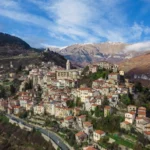 Veduta aerea del borgo di Triora tra le montagne del Parco delle Alpi Liguri, con le cime innevate sullo sfondo